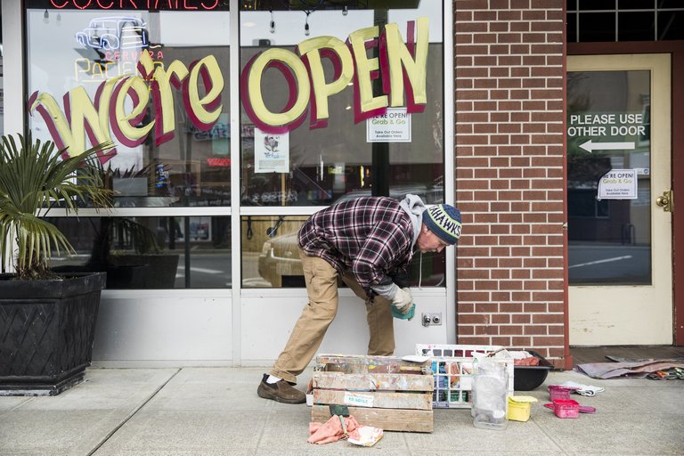 Someone painting a "We're Open" sign on a store window